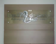 Placa de vidro temperado com letras em aço inox escovado e logomarca vinil adesivo.